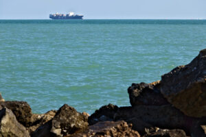 A cargo ship on the horizon in the green sea. Foto navi. Ships photo.