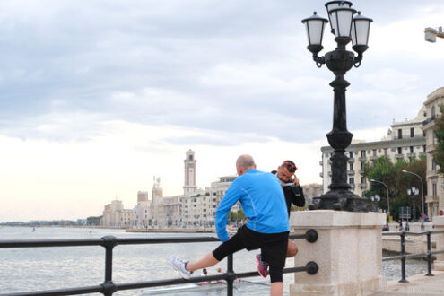 A man does gymnastics on the Bari waterfront. In the background the buildings of the city. - MyVideoimage.com