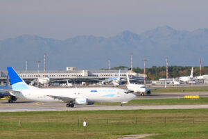 ASL Aviation Boeing 737-48E airplane on the Malpensa airport runway. In the background the buildings of Terminal 1 and parked airplanes. - MyVideoimage.com