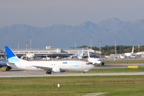 ASL Aviation Boeing 737-48E airplane on the Malpensa airport runway. In the background the buildings of Terminal 1 and parked airplanes. - MyVideoimage.com