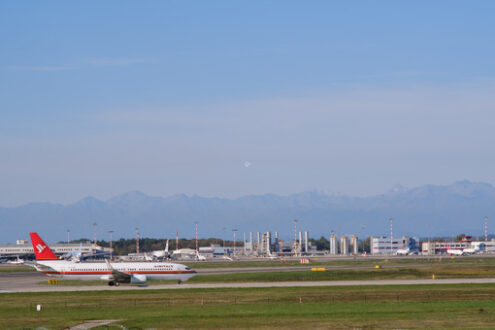 Air Italy Boeing 737-800  airplane on the Malpensa airport runway. 	In the background the power and thermal plant with chimneys. - MyVideoimage.com