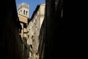 Alley of the city of Assisi with bell tower and stone houses. Narrow street of the city with the walls of the stone houses. Deserted road. - MyVideoimage.com