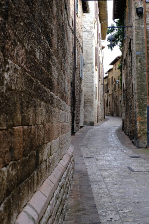 Alley of the city of Assisi with stone facades of historic houses. 	Narrow alleys of the city with the walls of the stone houses. Deserted road. - MyVideoimage.com | Foto stock & Video footage