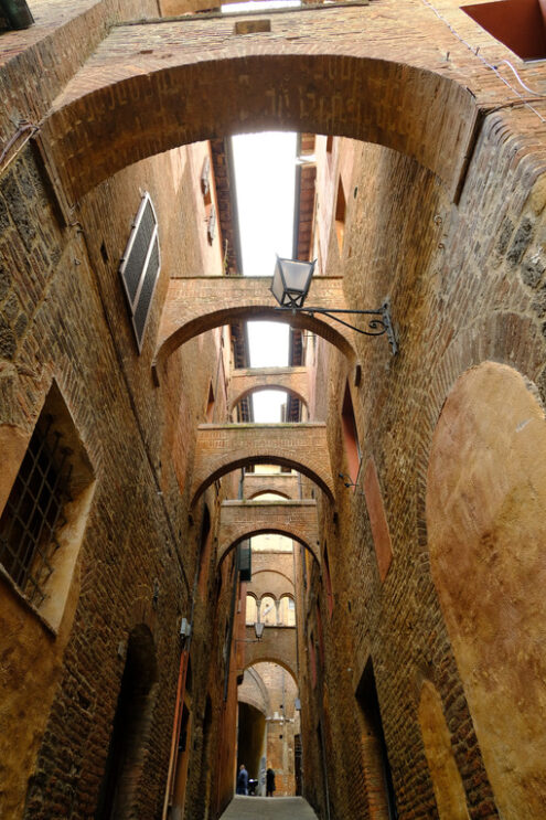 Alley with arches in the Tuscan city of Siena. Terracotta brick walls of the ancient houses. - MyVideoimage.com | Foto stock & Video footage