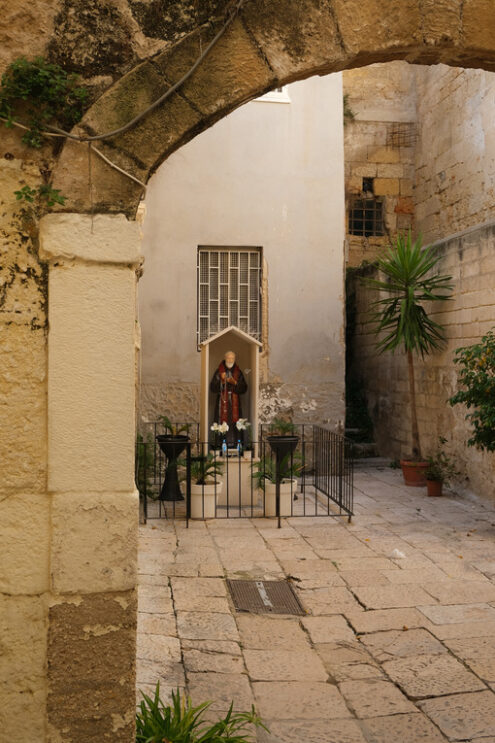 Altar with a statue of a saint in a courtyard in the historic center of Bari. Stone arch. Foto Bari photo.