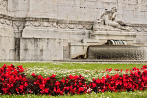 Altare della Patria o Vittoriano di Piazza Venezia a Roma. Particolare di una scultura e un prato con erba e fiori rossi. - MyVideoimage.it | Stock photo & Video footage