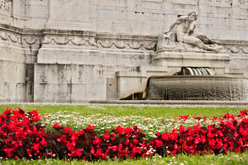 Altare della Patria o Vittoriano di Piazza Venezia a Roma. Particolare di una scultura e un prato con erba e fiori rossi. - MyVideoimage.it | Stock photo & Video footage