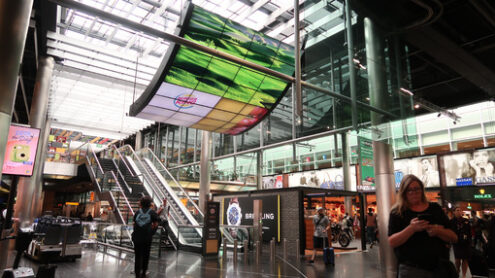 Amsterdam Airport. Amsterdam Airport Schiphol. Escalators. Airport terminal, shopping arcade with shops and people in transit. - MyVideoimage.com | Foto stock & Video footage