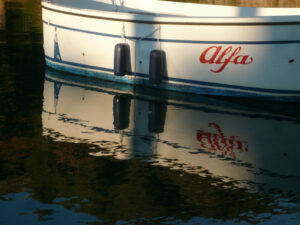 Ancient boat with the word Alfa moored at the port and illuminated by the light of the sunset. - MyVideoimage.com | Foto stock & Video footage