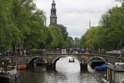 Ancient bridge on an Amsterdam canal. A boat runs along the cana - MyVideoimage.com