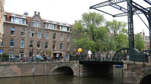 Ancient bridge on an Amsterdam canal. A boat runs along the cana - MyVideoimage.com