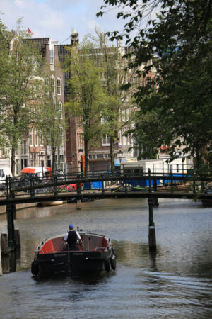 Ancient bridge on an Amsterdam canal. A boat runs along the cana - MyVideoimage.com