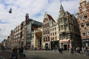 Ancient houses on a main street in Amsterdam. People and shops o - MyVideoimage.com