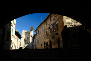 Ancient street of Assisi with an olive tree above a city gate. A brick arch covers an alley. - MyVideoimage.com | Foto stock & Video footage