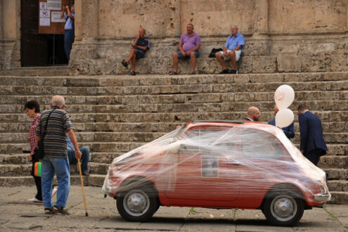 Antique red Fiat 500 car parked in the square of Massa Marittima. The car awaits the bride and groom at the cathedral wedding. Foto automobili. Cars photos.