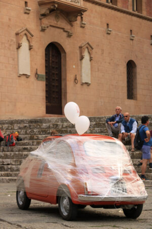 Antique red Fiat 500 car parked in the square of Massa Marittima. The car awaits the bride and groom at the cathedral wedding. Foto automobili. Cars photos.