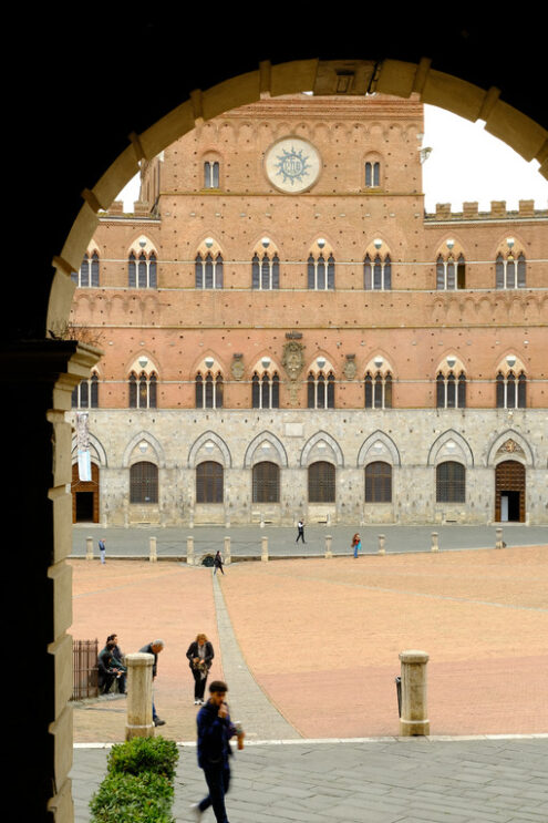 Arch overlooking Piazza del Campo in Siena. Background with municipal building in terracotta bricks. - MyVideoimage.com | Foto stock & Video footage