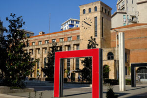 Arte in città. Tower with clock and red doors in the square. Foto stock royalty free. - MyVideoimage.com | Foto stock & Video footage