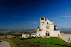 Assisi Basilica di San Francesco. Basilica of San Francesco with the lawn with green grass in front and the blue sky. Photo stock - MyVideoimage.com | Foto stock & Video footage