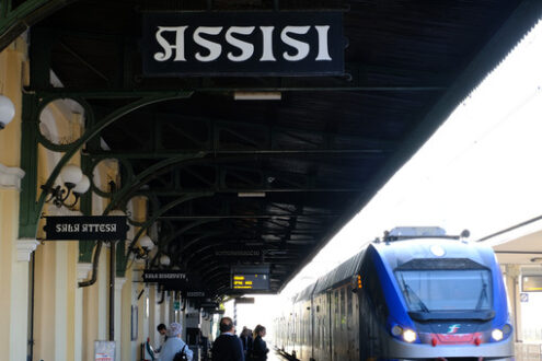 Assisi train station. A regional train is entering the Assisi station. Billboard and shelter. Città Italiane - MyVideoimage.com | Foto stock & Video footage