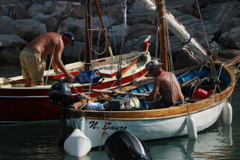 Barche colorate. Barche da pesca colorate ormeggiate al porto. Due pescatori preparano la vela. - MyVideoimage.com | Foto stock & Video footage