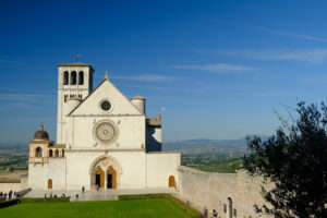 Basilica of San Francesco Assisi. Basilica of San Francesco with the lawn with green grass in front and the blue sky. - MyVideoimage.com | Foto stock & Video footage