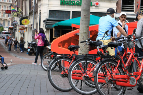 Bicycle parking at Amsterdam. Some guys on red public bikes. - MyVideoimage.com