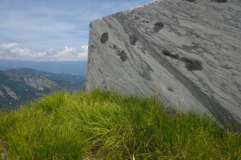 Blocco di marmo Block of white veined marble resting on a green lawn in the Apuan Alps. Foto stock royalty free. - MyVideoimage.com | Foto stock & Video footage