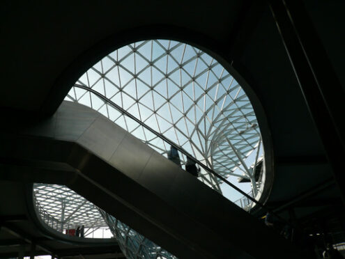 Businessman waiting inside a pavilion of the Milan fair. Modern architecture with steel and glass lattice structure. - MyVideoimage.com | Foto stock & Video footage