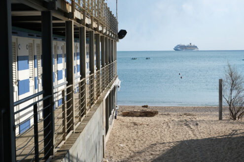 Cabins of a bathhouse in Liguria. Sea with cruise ship and boats in the background. - MyVideoimage.com | Foto stock & Video footage