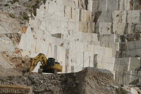 Carrara quarry and excavator. White Carrara marble quarry in Tuscany. Mountains of the Apuan Alps, blue sky and a mechanical excavator. - MyVideoimage.com | Foto stock & Video footage