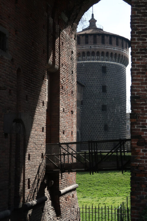 Castello sforzesco Milano. Torre circolare. Circular brick tower of the Sforzesco Castle in Milan. Iron bridge and green lawn. MIlano foto. - MyVideoimage.com | Foto stock & Video footage