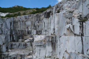 Cava di marmo sulle Alpi Apuane. Wall of a white marble quarry under the mountain. Foto stock royalty free. - MyVideoimage.com | Foto stock & Video footage