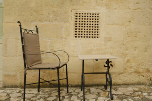 Chair whit table. Chair with iron table in a courtyard in the city of Matera. Beige stone wall with marble air grilles. - MyVideoimage.com | Foto stock & Video footage