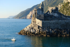 Chiesa Portovenere a picco sul mare. Barca bianca nel mare e le rocce nei pressi delle Cinque Terre in Liguria. - MyVideoimage.com | Foto stock & Video footage