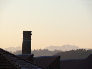 Chimney of old abandoned industrial complex. Work of industrial archaeology. In the background the profile of the mountains (Alps) - MyVideoimage.com