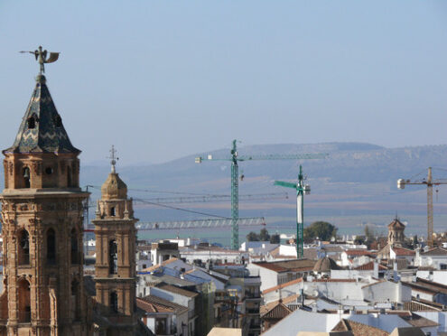 Building site in Spain. Church bell tower and construction site crane.