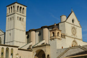 Church of San Francesco in Assisi with the stone wall. The basilica built in Gothic style houses the frescoes by Giotto and Cimabue. - MyVideoimage.com