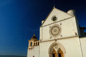 Church of San Francesco in Assisi with the stone wall. The basilica built in Gothic style houses the frescoes by Giotto and Cimabue. - MyVideoimage.com