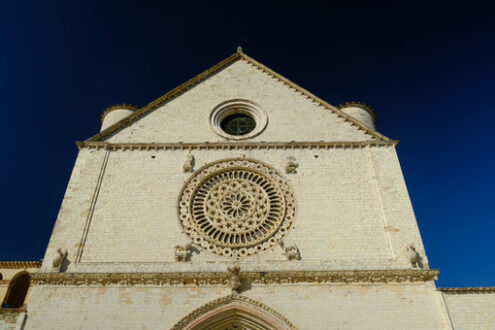 Church of San Francesco in Assisi with the stone wall. The basilica built in Gothic style houses the frescoes by Giotto and Cimabue. - MyVideoimage.com