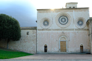 Church of San Pietro in Assisi with the stone wall. Romanesque church with a façade with three light-colored rose windows. - MyVideoimage.com