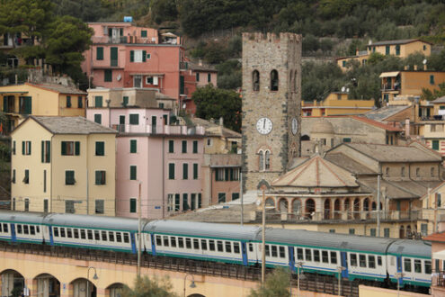 Cinqueterre train. Train passes inside the village of Monterosso al Mare. In the background the church with the bell tower. - MyVideoimage.com | Foto stock & Video footage