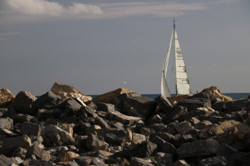 Cliff with sailboat. Cliff by the sea with a view of a sailboat. - MyVideoimage.com | Foto stock & Video footage