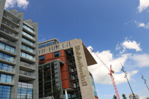 Construction crane in the city center. Blue sky background. Museum flags and conservatory building. - MyVideoimage.com