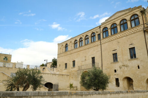 Convento di Matera. Facade of the Convent of Sant’Agostino in Matera. Courtyard with olive trees with leaves moving in the wind. - MyVideoimage.com | Foto stock & Video footage