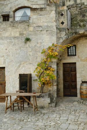 Courtyard in Matera wit vine plant. Vine plant grown in a stone planter in the Sassi of Matera. Courtyard of a house with a wooden table and a wine barrel. - MyVideoimage.com | Foto stock & Video footage