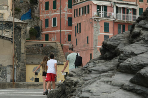 Dad with children walking among typical Ligurian houses in the town of Vernazza. In the foreground the cliff overlooking the sea. Royalty free stock photography. - MyVideoimage.com | Foto stock & Video footage