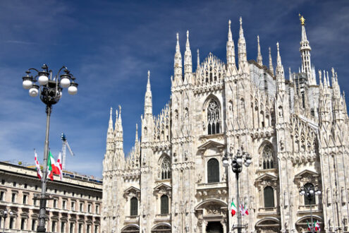 Duomo di Milano. La facciata del Duomo. Bandiere che sventolano sul cielo blu. - MyVideoimage.com | Foto stock & Video footage