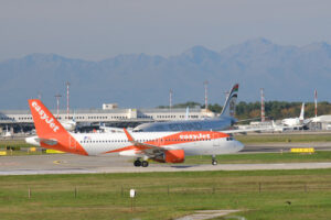 Easyjet Airbus airplane maneuvering on the Malpensa airport runway. In the background the buildings and Etihad planes. - MyVideoimage.com