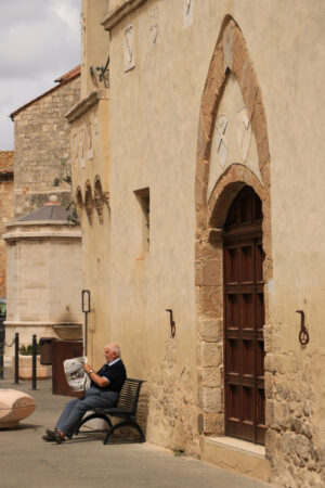 Elder reads the newspaper sitting on a bench in front of the Palace. - MyVideoimage.com | Foto stock & Video footage